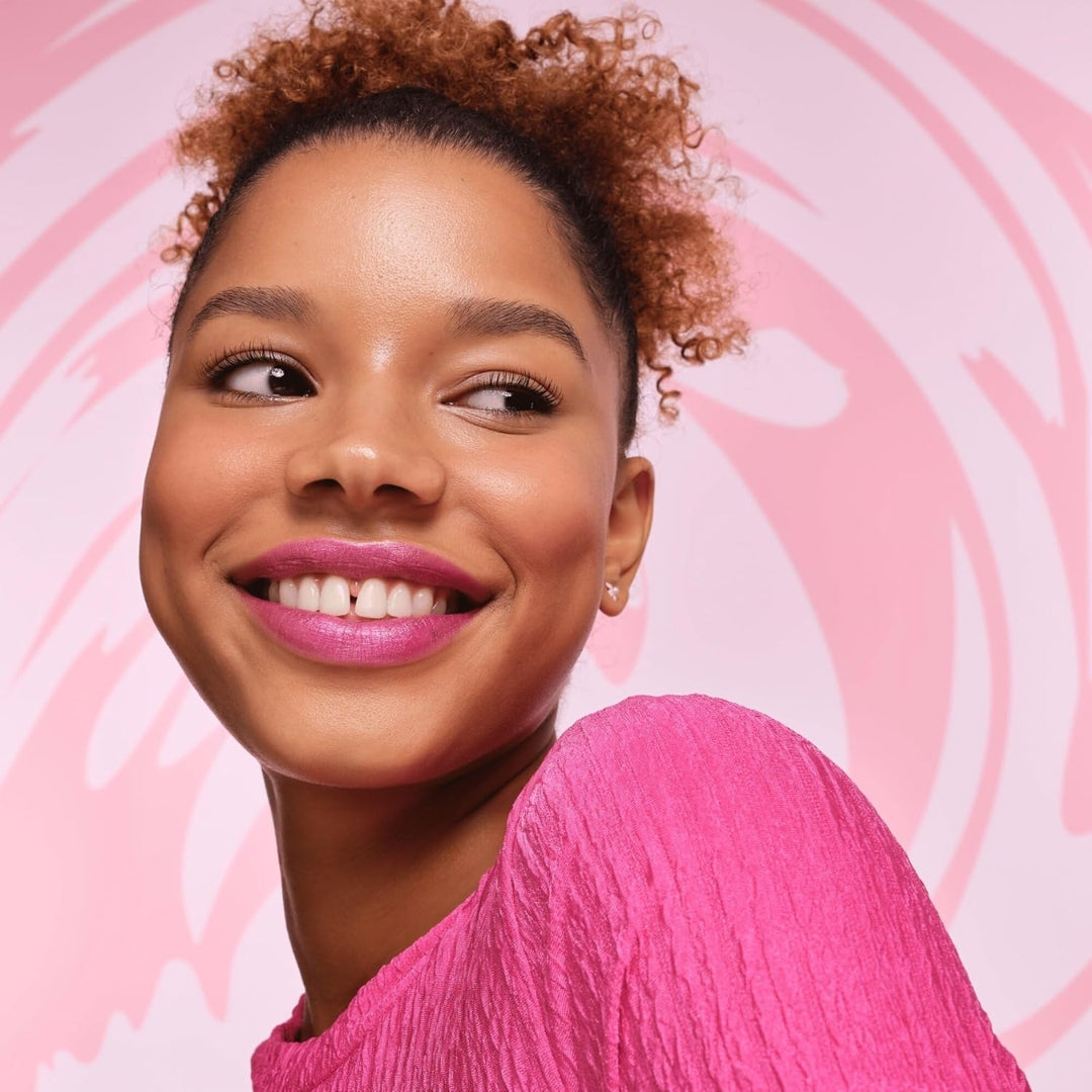 Woman with pink lipstick and pink top against a pink heart patterned background