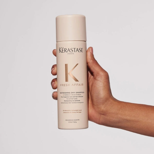 Kérastase Fresh Affair dry shampoo bottle held by a hand on a light gray background